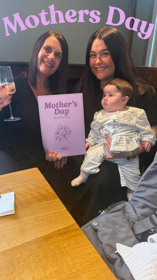 The video promotes a Mother's Day special at Prezzo, an Italian restaurant. It starts with shots of the restaurant's exterior and promotional signage for the event. The video then shows a family group, including a mother, daughter, and a baby, celebrating at a table. They are seen toasting with prosecco and enjoying various dishes. The food featured includes appetizers like olives and fried cheese balls, and main courses such as a rigatoni pasta dish, a chicken and red pepper pizza, and sides of tenderstem broccoli, fries, and roasted potatoes. The video concludes with shots of the restaurant's interior, including the bar and dining areas.