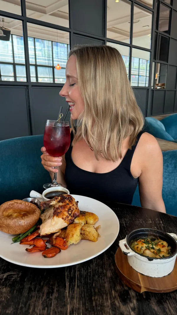 The video showcases a Sunday roast at No.29 in Battersea, London.  The setting is a modern, stylish restaurant. The food includes roast chicken, Yorkshire pudding, roasted potatoes and vegetables, gravy, and cranberry sauce. For dessert, a crumble with ice cream is shown. Two cocktails, an Aperol Spritz and another lighter-colored cocktail, are also presented. The food is visually appealing, with warm lighting and close-up shots highlighting textures and details.