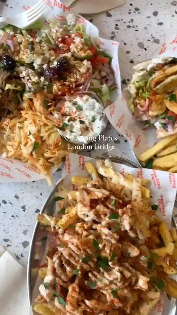 The video showcases various dishes from Smashing Plates, a Greek takeaway restaurant in London Bridge.  It features halloumi souvlaki wraps, a loaded green salad with vegan gyros, loaded oregano fries with chicken gyros, and toasted pitta bread.  The presentation emphasizes abundant portions and vibrant colors.  No specific dietary restrictions are explicitly mentioned beyond the inclusion of vegan gyros.