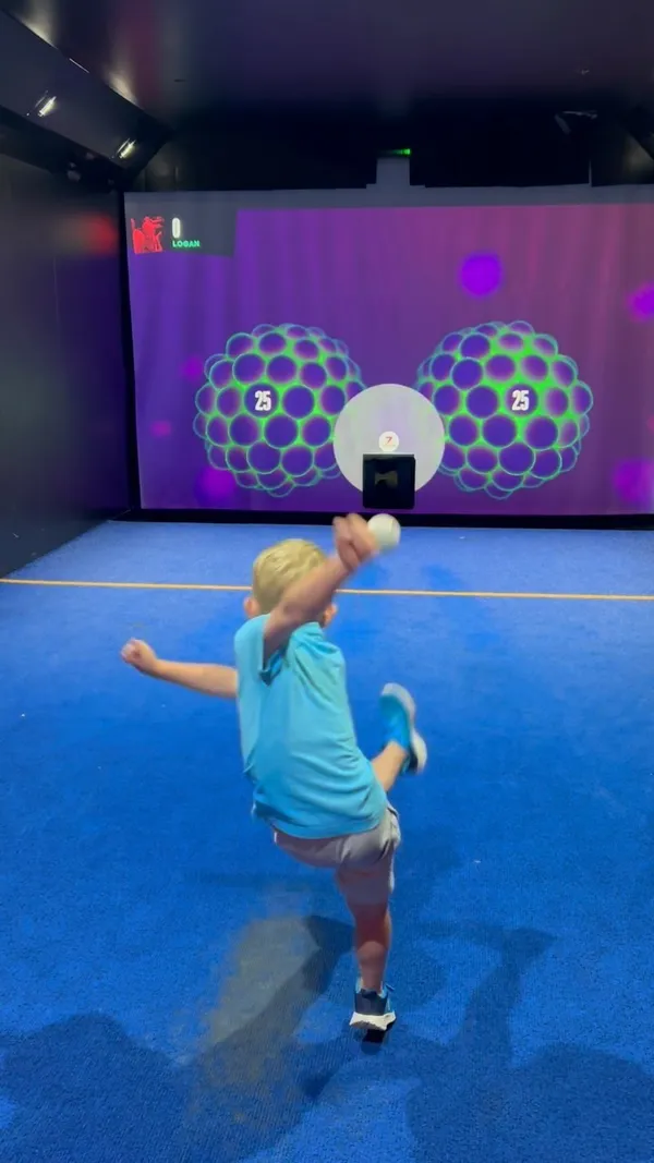 The video showcases a family's experience at TOCA Social, an entertainment venue at The O2 arena in London. It features various interactive football games projected onto a screen, with the family members actively participating.  No specific food items are shown, though drinks are visible, and the caption mentions food is available at the venue. The focus is on the fun and engaging activities available, rather than a detailed food and drink presentation.