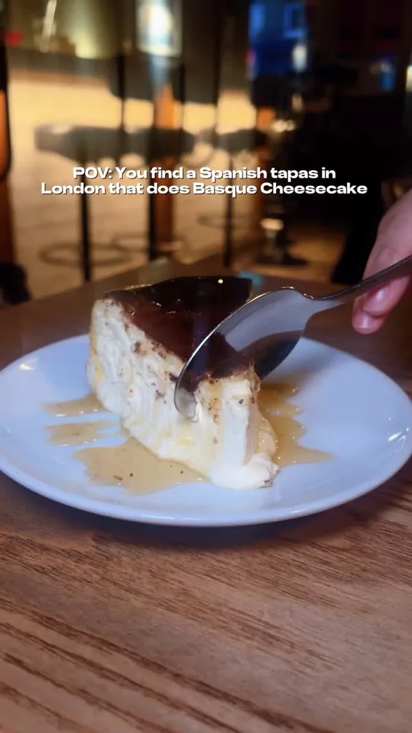 The video showcases a meal at Salt Yard restaurant in London.  It features various tapas dishes such as roasted peppers, risotto arancini, grilled prawns, chickpeas with grilled squid, and duck. The main focus is the Basque cheesecake, with multiple close-up shots highlighting its texture and presentation.  The video is accompanied by upbeat music and text overlays promoting the restaurant and its set menu.