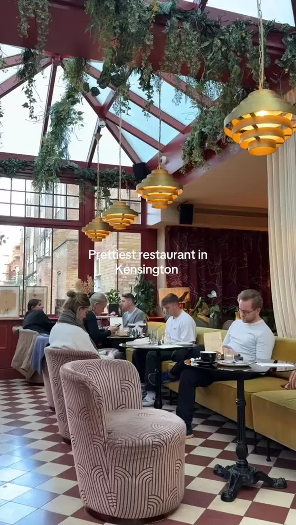The video showcases the interior and exterior of Eve restaurant in Kensington. It features shots of the dining area with people, the exterior entrance, the garden seating area, the bar area, the menu, two Aperol Spritz cocktails, Parmesan fries, a Margherita pizza, and a pepperoni pizza with burrata. It highlights the restaurant's aesthetic and food offerings.
