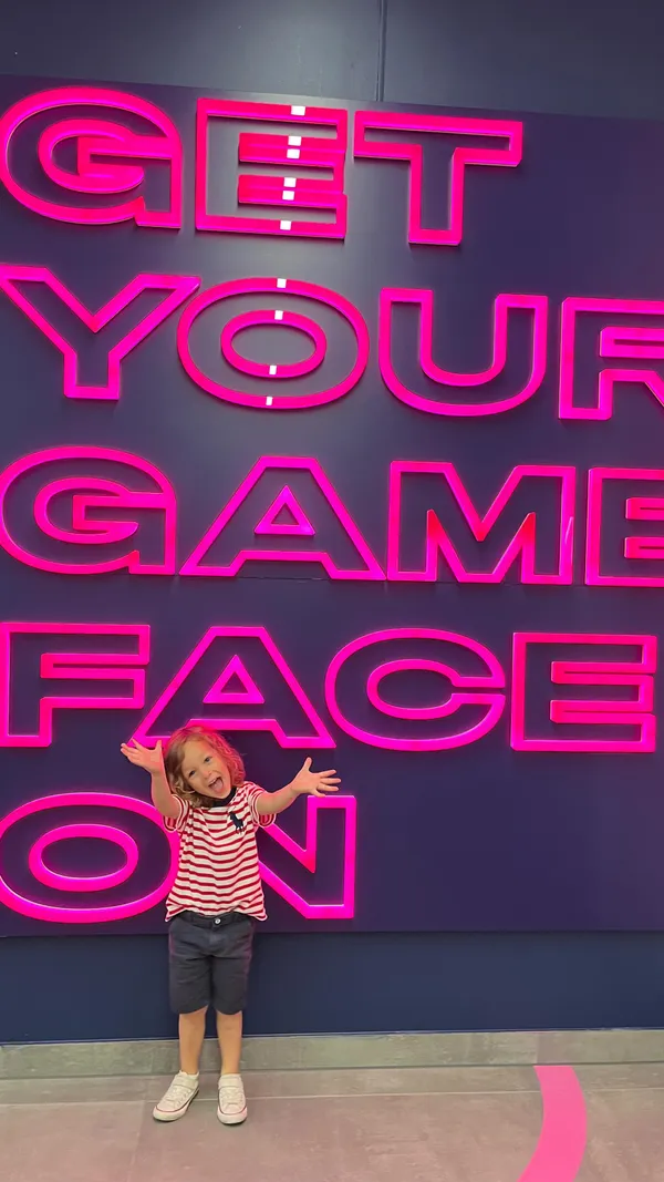 The video showcases a family's visit to TOCA Social, an entertainment venue featuring interactive football games.  The video shows various games, including an elimination game where players kick a ball to knock out opponents' pictures on a screen. Adults and children are shown playing the games. There is a brief shot of two cocktails.