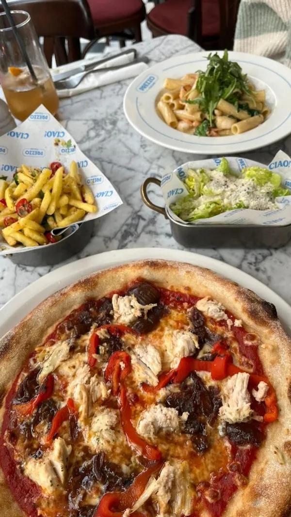 The video showcases a meal at the newly refurbished Prezzo Italian restaurant in Nottingham. It begins with an exterior shot, then moves inside to show a variety of dishes and drinks. The items featured include cocktails, dough balls with dip, fried mozzarella sticks with a prominent cheese pull, a pasta dish being topped with freshly grated parmesan, a pizza, seasoned fries, a Caesar salad, and two desserts, one of which is a chocolate dish with ice cream.