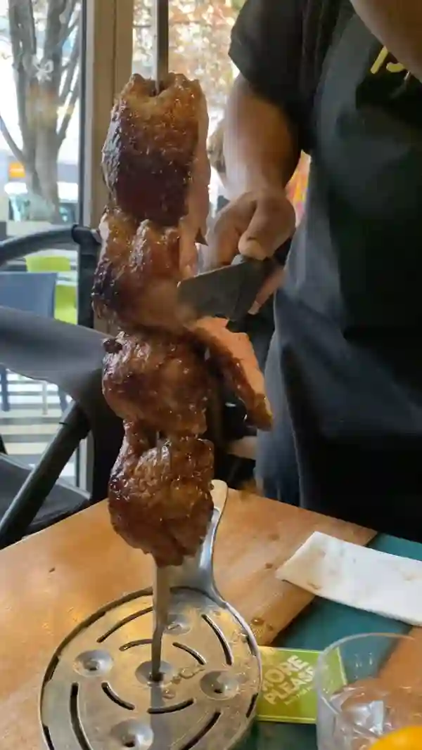 The video showcases Preto Brazilian Steakhouse, highlighting its rodizio-style dining experience.  It features a variety of buffet items (salads, vegetables, fried foods), and various cuts of grilled meats served tableside.  The presentation is focused on the abundance and variety of food, with quick shots of the buffet and the meat service. Mocktails and cocktails are briefly featured. No specific dietary information is provided.