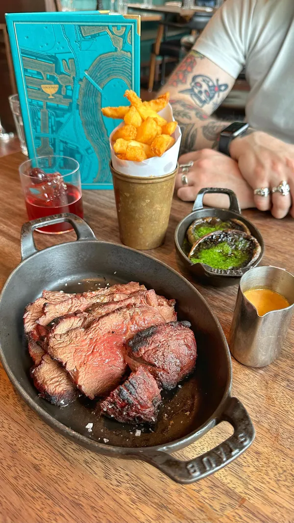 The video showcases a meal at Hawksmoor restaurant in Canary Wharf, London.  It features various dishes including steak with sauce, chips, creamed spinach, Yorkshire puddings, and sticky toffee pudding.  Cocktails are also shown. The presentation emphasizes high-quality ingredients and visually appealing plating.  No dietary information is explicitly provided.