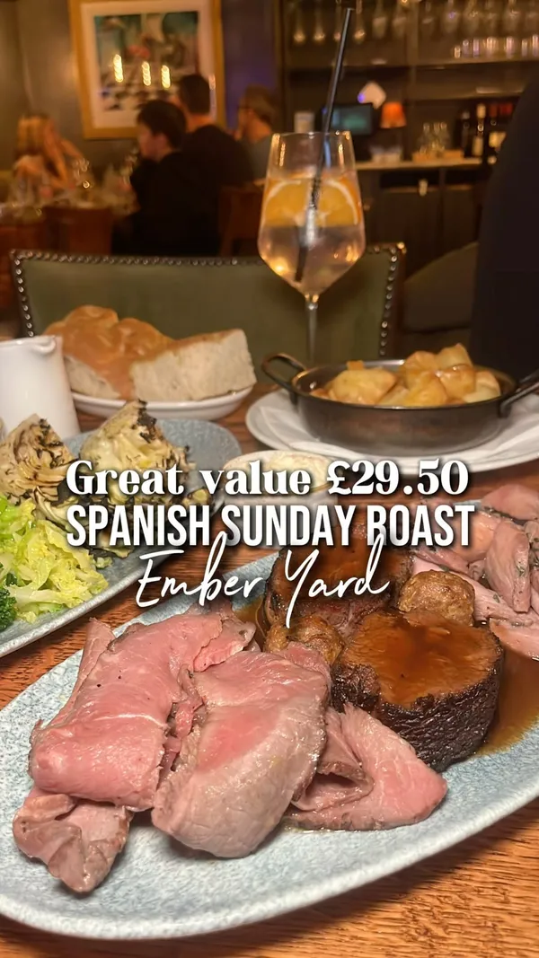 The video showcases a Spanish-inspired Sunday roast at Ember Yard restaurant in London. It features close-up shots of the roast beef, featherblade, and sirloin, along with crispy roast potatoes and seasonal greens (charred cabbage and broccoli). The dessert includes a mille-feuille and churros with chocolate dipping sauce. The restaurant's ambiance is also briefly shown.