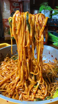 Plate of Very Lazy Chilli Garlic Noodles topped with spring onions and greens, ready to serve in 15 minutes.