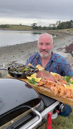 Surf & Turf platter with ribeye steak, mussels, langoustines, and prawns on a Weber grill by Strangford Lough, Northern Ireland.