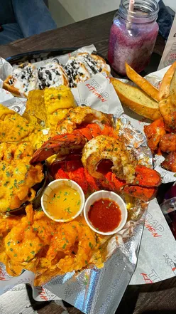 Delicious seafood feast at Trap Kitchen in NW London: lobster tails, bang bang prawns, and Hard Slushie cocktail.