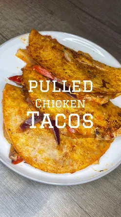 Pulled chicken tacos with peppers, onions, cheese, and spices in crispy tortillas, perfect for a flavorful dinner.