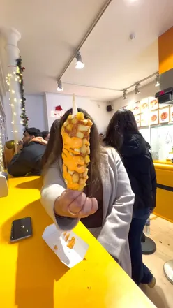 Cheesy potato mozzarella corn dog with spicy mayo at Bunsik in London, a popular Korean street food spot.