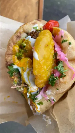 Delicious falafel wrap from Pockets UK at Netil Market, featuring fresh veggies and sauces in steamed pita.