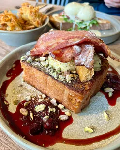 Homeground Cafe's Pain Perdu French Toast with pistachio cheesecake, berry compote, and bacon, plus ham hock eggs Benedict and hash browns in Windermere.
