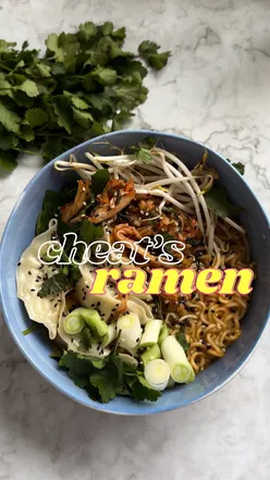 Bowl of instant ramen topped with beansprouts, gyoza, kimchi, spring onions, and coriander for a quick meal.