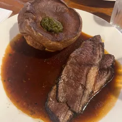 Roast Highland topside of beef with bone marrow gravy, Yorkshire pudding, pomme anna, veggies, smoked mash, and garlic hispi cabbage at Ox Club Leeds.