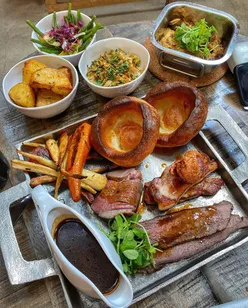 Sunday roast at The Brick Yard with beef, pork loin, chicken fat roasties, blue cheese broccoli, and Yorkshire pudding.