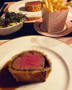 Beef Wellington with truffle jus at Bob Bob Ricard, London, featuring a 'Press for Champagne' button in a cozy booth setting.