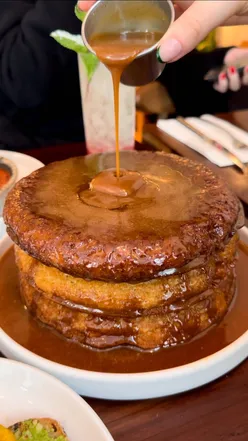 Fluffy pancakes drizzled with hazelnut praline sauce, perfect for brunch in Notting Hill, London.