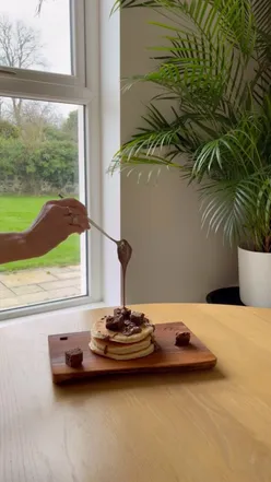 Indulgent pancake party box with 20 fluffy pancakes, maple syrup, cinnamon cream, blueberry compote, salted caramel sauce, brownie chunks, and chocolate hazelnut ganache from French Village for Pancake Tuesday.