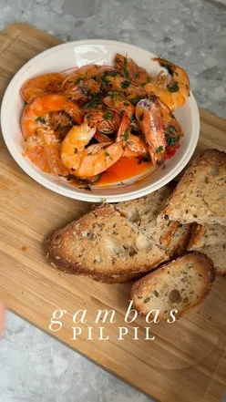 Delicious homemade Gambas Pil Pil with garlic, chilli, and prawns, perfect for dipping bread in flavorful oil.