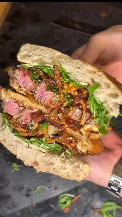 Steak sandwich with toasted ciabatta, shoestring fries, chimichurri, caramelized onions, roasted garlic Dijon aioli, rocket, Parmesan.