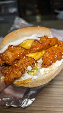 Double spicy dipped chicken burger from O.G. Birmingham, topped with sauce and served with fries.