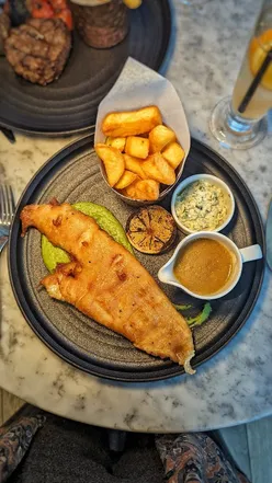 Tir a Môr restaurant at voco St. David's Cardiff, with waterside views, serves Welsh dishes like truffled honey Camembert and beer-battered fish.