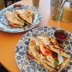 Bacon and egg naan with cream cheese, tomato-chili jam, streaky bacon, and fried egg at Dishoom Brighton on East Street.