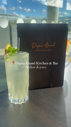 Colorful spread of Indian dishes including mocktail, samosa chaat, saag aloo, and chicken biryani at Dipna Anand Kitchen.