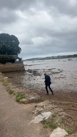 Man searches beach for treasure; woman awaits red wine under cloudy sky. #Topsham #Bristol #SundayVibes