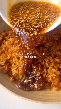 Crispy rice salad with cucumber, spring onions, herbs, and spicy dressing, perfect for a refreshing side dish.