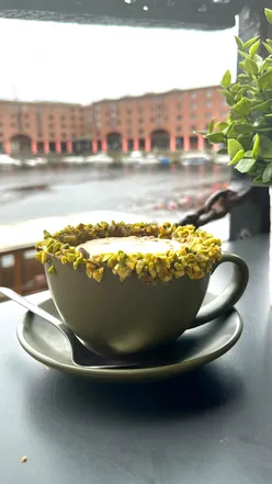 Pistachio cappuccino at Francies, Albert Dock, Liverpool, showcasing creamy texture and vibrant color.