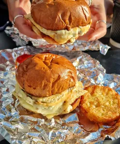 Vegan sausage breakfast sando with cheese, sriracha mayo, and onion jam on a potato bun at Grandad Needs His Medicine, Swansea.