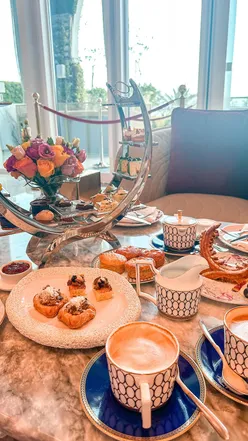 Afternoon tea at Raffles Doha with hot beverages and a waffle shaped like iconic towers, enjoyed in a stunning lobby.