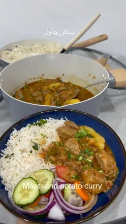 Lamb and potato curry with sautรฉed onions, garlic, and spices, garnished with coriander, served with rice.