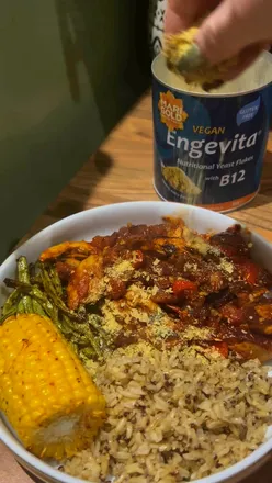 A vibrant spicy chili with seitan, green beans, corn on the cob, and rice, perfect for vegan meals.