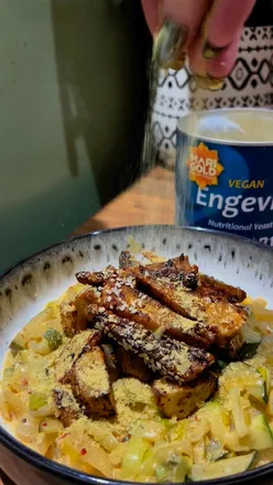 Creamy cheesy leeks and courgettes with crispy potatoes, tempeh, and extra nooch, perfect for a cozy vegan meal.