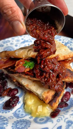 Festive brie-stuffed bacon naan at Dishoom with cranberry-chilli chutney, perfect for breakfast lovers. #Dishoom #Breakfast