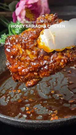 Crispy honey sriracha chicken thighs with cornflakes, drizzled in spicy-sweet sauce, perfect for air fryer cooking.