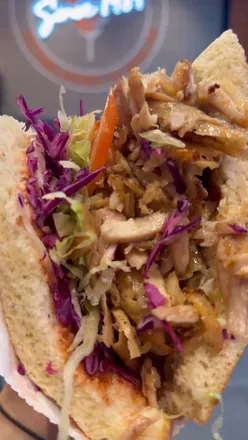 Toasted sesame waffle bread filled with meat, lettuce, tomato, red cabbage, and sauces at German Doner Kebab.