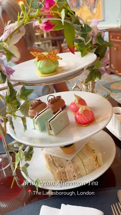 Elegant Bridgerton-themed afternoon tea at The Lanesborough, London, featuring cakes, scones, and tea in a charming setting.