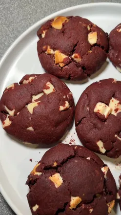 Freshly baked red velvet cookies with white chocolate chunks on a cooling rack, perfect for red velvet lovers and baking enthusiasts.