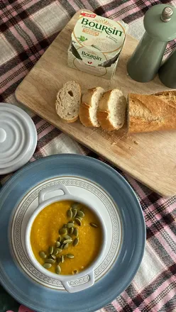 Hearty butternut, swede, and carrot soup with lentils and beans, garnished with seeds, served with crusty bread and vegan butter.