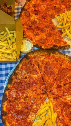 Close-up of a gooey cheese pull from a pizza slice at Frank's Pizza and Subs, Southside Glasgow. Wine glass in background.