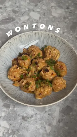 Homemade pork and prawn wontons ready to be boiled, served with a spicy dipping sauce.