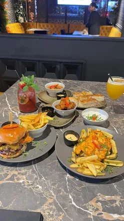 Delicious spread at Fomo Lounge Cardiff: mozzarella sticks, fried chicken bites, tzatziki, burgers, mocktails, and desserts.