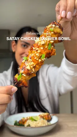 Satay chicken skewers with peanut butter dressing, wholegrain rice, and broccoli in a bowl; healthy, high-protein meal.