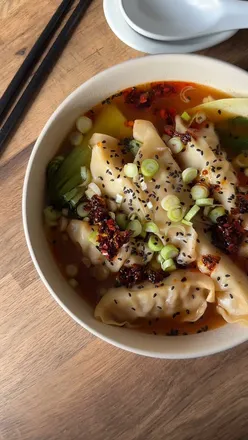 Bowl of steaming dumpling soup with wontons and chili oil, perfect for a quick Asian lunch.