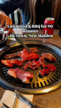 Unlimited Korean BBQ feast at K-Town in New Malden, London, featuring grilled meats and vibrant side dishes.